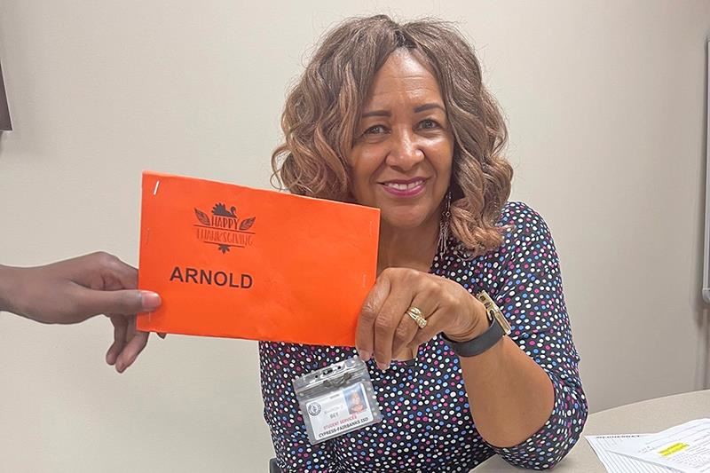 Sharon Bey, Families in Transition counselor, is given an envelope with $50 grocery store gift cards to help CFISD families.